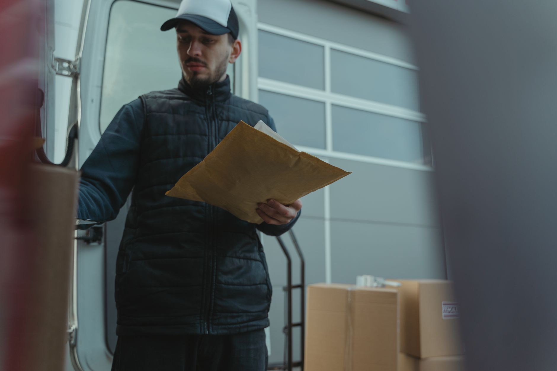 Delivery worker holding a clipboard near parcels